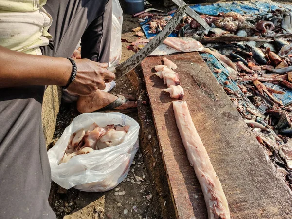 Fresh fish fillets on a board.  Fish market in India.  The seller cuts fish fillets for sale with a large crooked knife