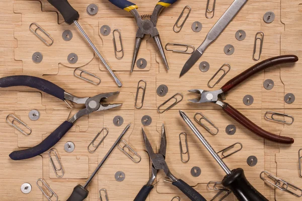 Schroevendraaiers, mes, draad frezen, Tang, knoppen en paperclips op een houten oppervlak. Workshop schaalmodellen. — Stockfoto