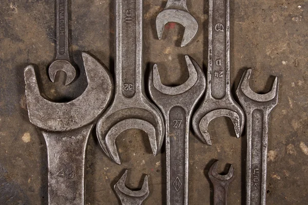 Set of wrenches on oiled floor of the garage