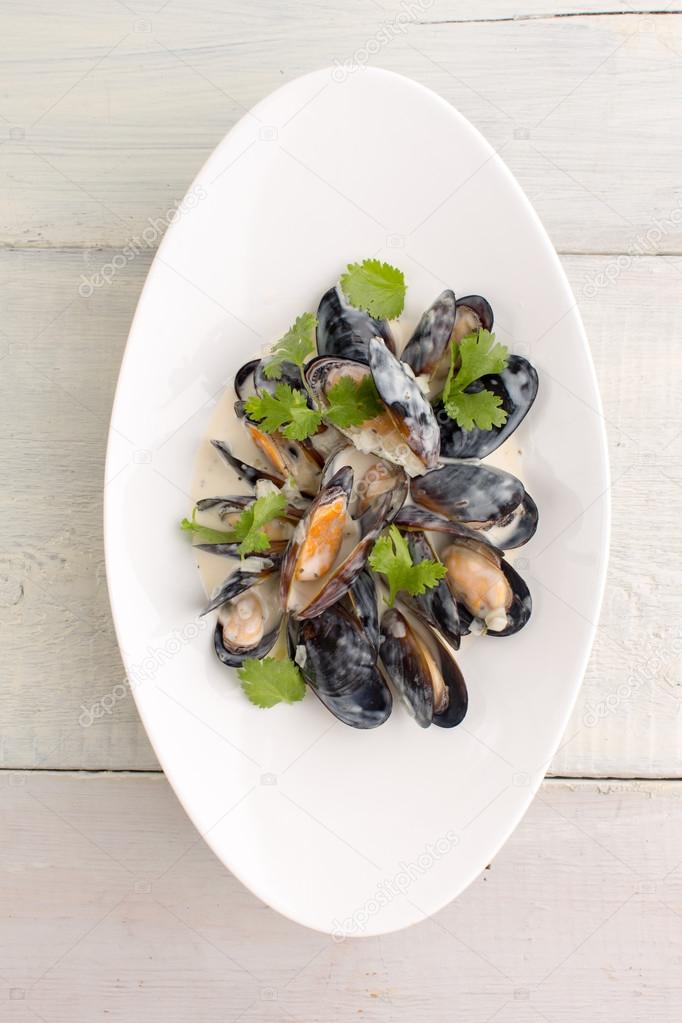 Mussels in a plate on white wooden background