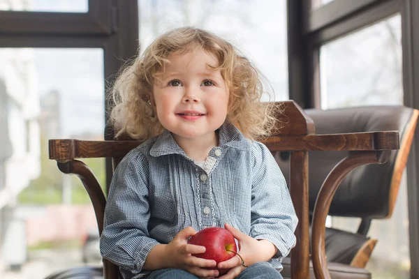 Retrato de criança sentada na cadeira com maçã — Fotografia de Stock