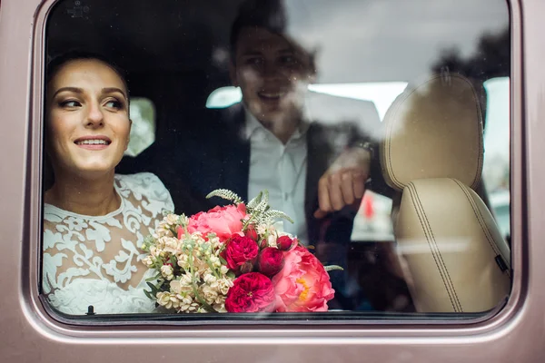 Bride and groom looking SUV through the car window — Stock Photo, Image