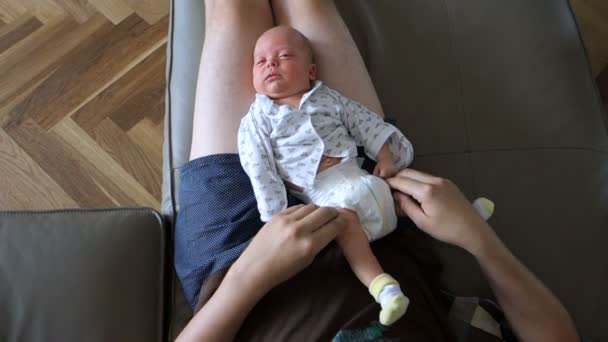 爸爸让按摩腿刚出生的婴儿在膝上 — 图库视频影像