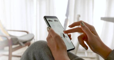 Akıllı telefon ekranına göz atan kadın kıyafet sipariş ediyor