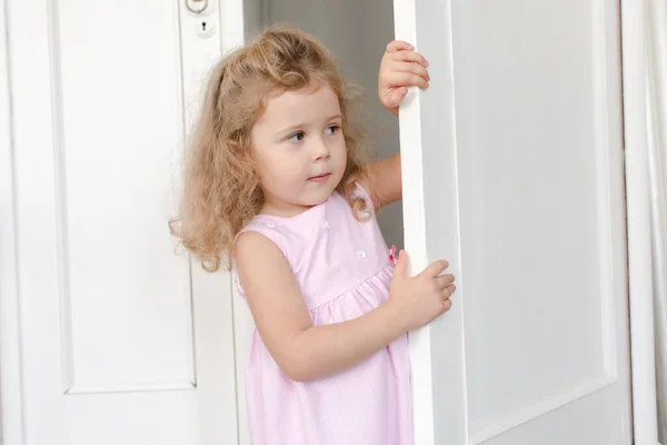 Linda chica espiando fuera de la puerta en la habitación — Foto de Stock