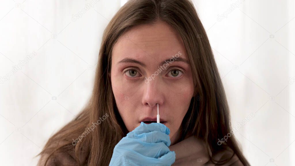 Woman takes swab from nasal mucosa using medical tampon