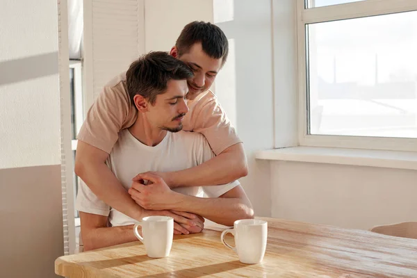 Pareja gay abrazándose durante el desayuno en casa —  Fotos de Stock