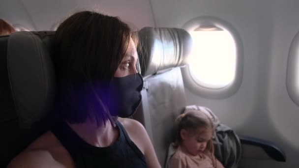 Γυναίκα με μάσκα και μικρή κόρη κάθεται στην καμπίνα του αεροπλάνου — Αρχείο Βίντεο