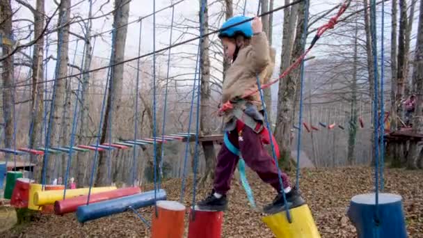 Garçon courageux dans le casque monte les escaliers à des cours de corde haute — Video