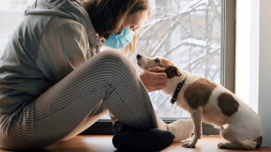 Pencerede maskeli bir kadın ve bir köpek.