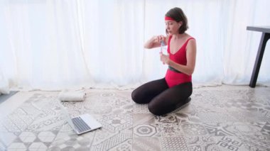 Bayan laptopa karşı su içiyor idmana hazırlanıyor.