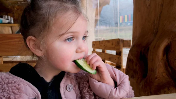 A kislány friss uborkát eszik. — Stock Fotó