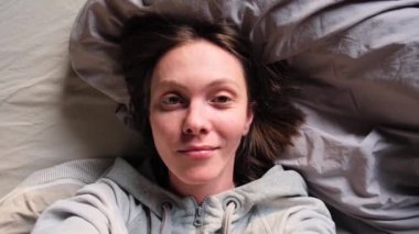 Sırtüstü uzanmış kameraya bakan mutlu kadın.