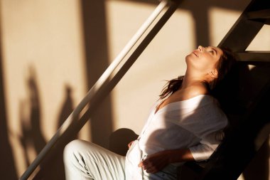 Modern apartmanda merdivenlerde çıplak ayaklı genç bir kadın oturuyor.