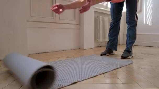 Frau rollt graue Yogamatte aus, um Sportübungen am Boden zu machen — Stockvideo