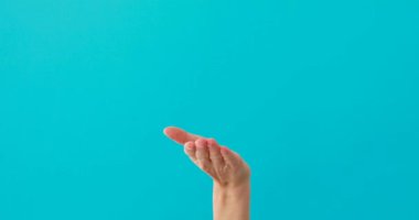 Kadın, bir şeyin üzerinde avuç içi turkuaz arka planda görünüyor.