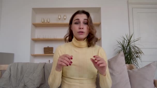 Jonge vrouw praat met camera zitten op comfortabele bank — Stockvideo