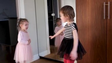 Küçük kız, oda elbiseli kardeşine bakıyor.