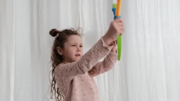 Urocza Dziewczynka Długimi Kręconymi Włosami Próbuje Strzelać Kolorowe Plastikowe Zabawki — Wideo stockowe