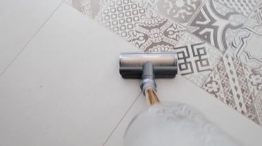 Döşemeleri ıslak ve kuru süpürge kullanarak süpürüyor.
