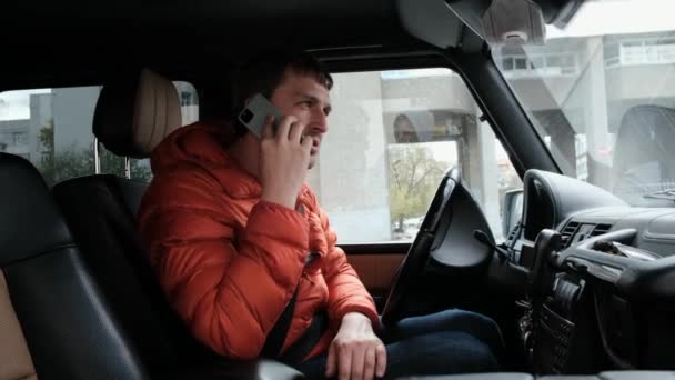 Conductor en chaqueta habla por teléfono sentado en el salón de coches — Vídeo de stock