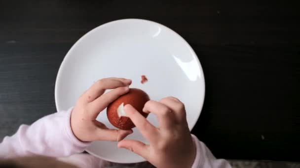 Chica pela huevo de color por encima del plato en la mesa en Pascua — Vídeo de stock