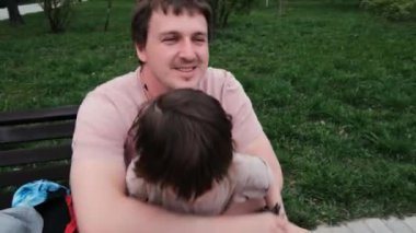 Smiling father holds naughty little kid boy and talks