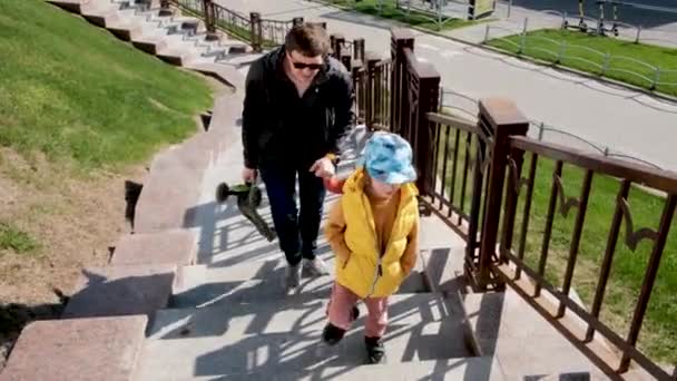 Smiling dad walks with small boy and girl up large stairs — ストック動画