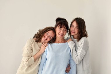 Gülümseyen anne kızlarını kucaklıyor ve kameraya bakıyor.
