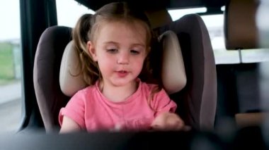 At kuyruklu küçük kız oturur ve araba koltuğunda konuşur.