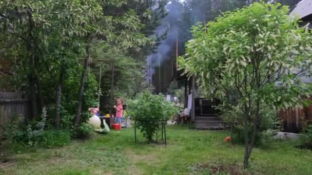 女の子近くスイングで民家の裏庭で煙で空気 — ストック動画