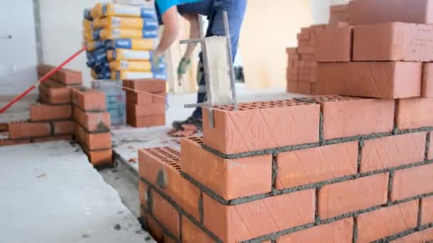 Rijpere werknemer kiest en hakt baksteen op de bouwplaats — Stockvideo