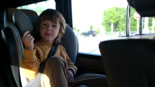 Joyeux jeune garçon rit près de la fenêtre à l'intérieur du véhicule en mouvement — Video