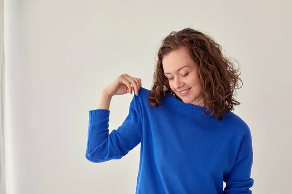 Улыбающаяся женщина в синем вязаном свитере на белом фоне — стоковое фото