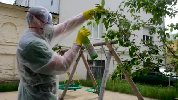 Man in protective suit sprays pesticide on tree by house — Stock Video