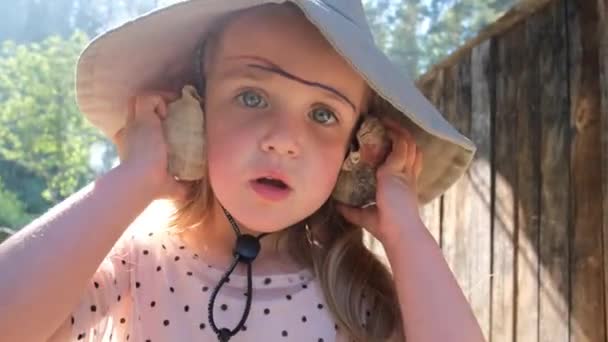 A kislány kagylóhangokat hallgat a nyári házban. — Stock videók