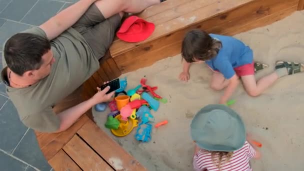 Мальчик копает песок с грабли проводить время с сестрой и отцом — стоковое видео