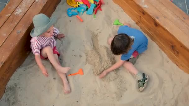 Chłopak kopie piasek z grabiami spędzając czas z siostrą — Wideo stockowe