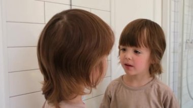 Tatlı çocuk aynada kendini inceliyor.