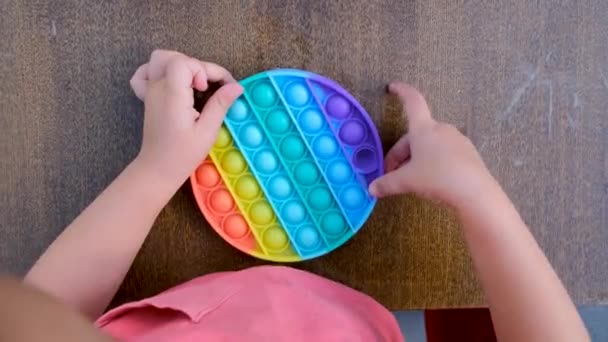 Child plays with pop it on table — Stockvideo