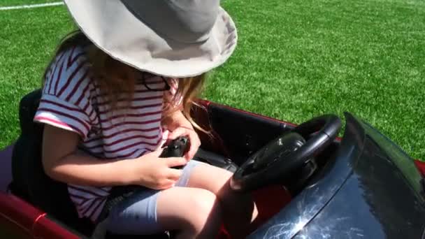 Fiatal lány kioldja csatok biztonsági öv ül a kis játék autó — Stock videók