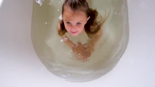 Zabawna dziewczynka z mokrymi włosami i niebieskimi oczami skacze do wody — Wideo stockowe