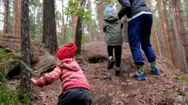 Anne, çocuğun elini tutuyor. Küçük bir parkta yamaç yolunda yürüyor.
