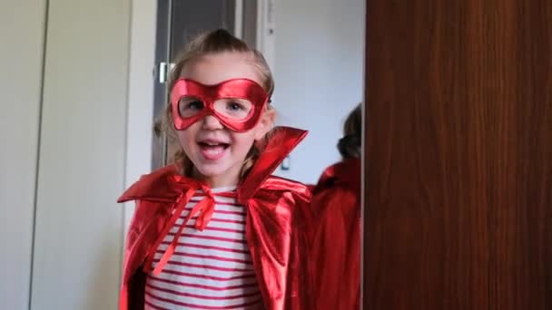Deliciosa niña preescolar en máscara roja en los ojos y capa — Vídeos de Stock