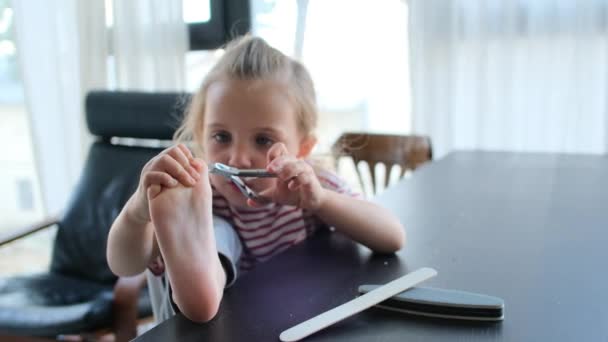 Забавная маленькая девочка режет ногти на ножницах из металла — стоковое видео
