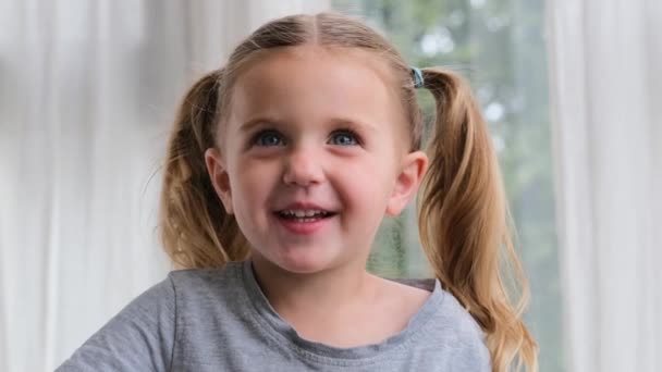 Graciosa niña sonriendo mirando a la cámara en casa — Vídeos de Stock