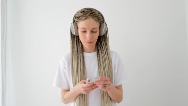 Mujer de blanco con coletas funciona con smartphone — Vídeos de Stock