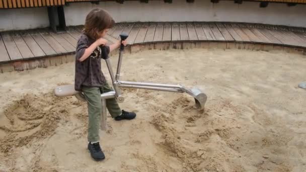 Interessado pré-escolar menino escavações com escavadeira de metal pequeno — Vídeo de Stock