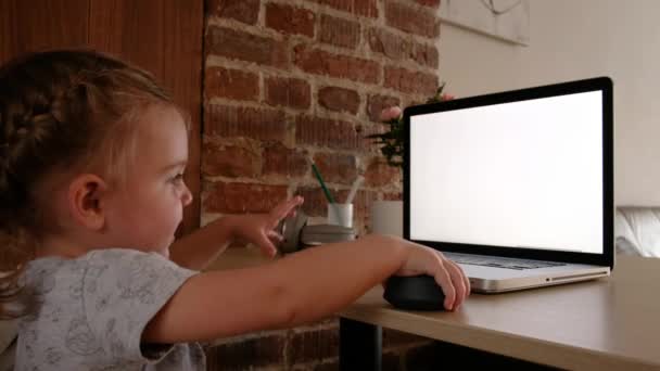Smilende sød lille pige ved hjælp af bærbar computer ser på skærmen – Stock-video