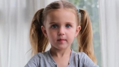 Saçları örgülü komik anaokulu çocuğu ciddi bir yüz ifadesi takınıyor.